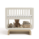 Santorini frosted oat with driftwood bassinet front view with baby items on bottom shelf