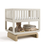 Santorini frosted oat with driftwood bassinet angle view with baby items on bottom shelf