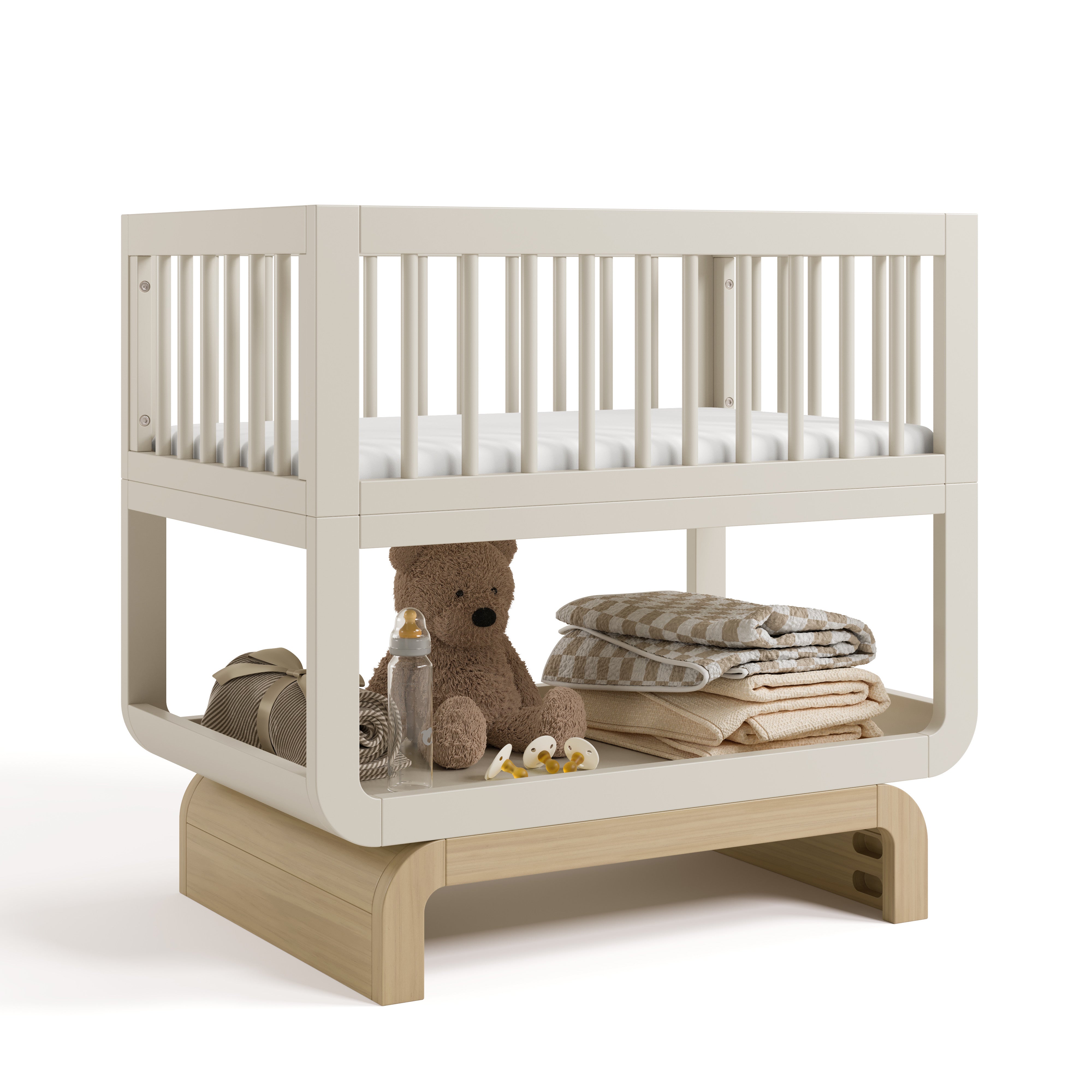 Santorini frosted oat with driftwood bassinet angle view with baby items on bottom shelf