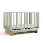 Baby crib in two-tone sage and natural wood colorway, at an angled view (Sage with Driftwood)
