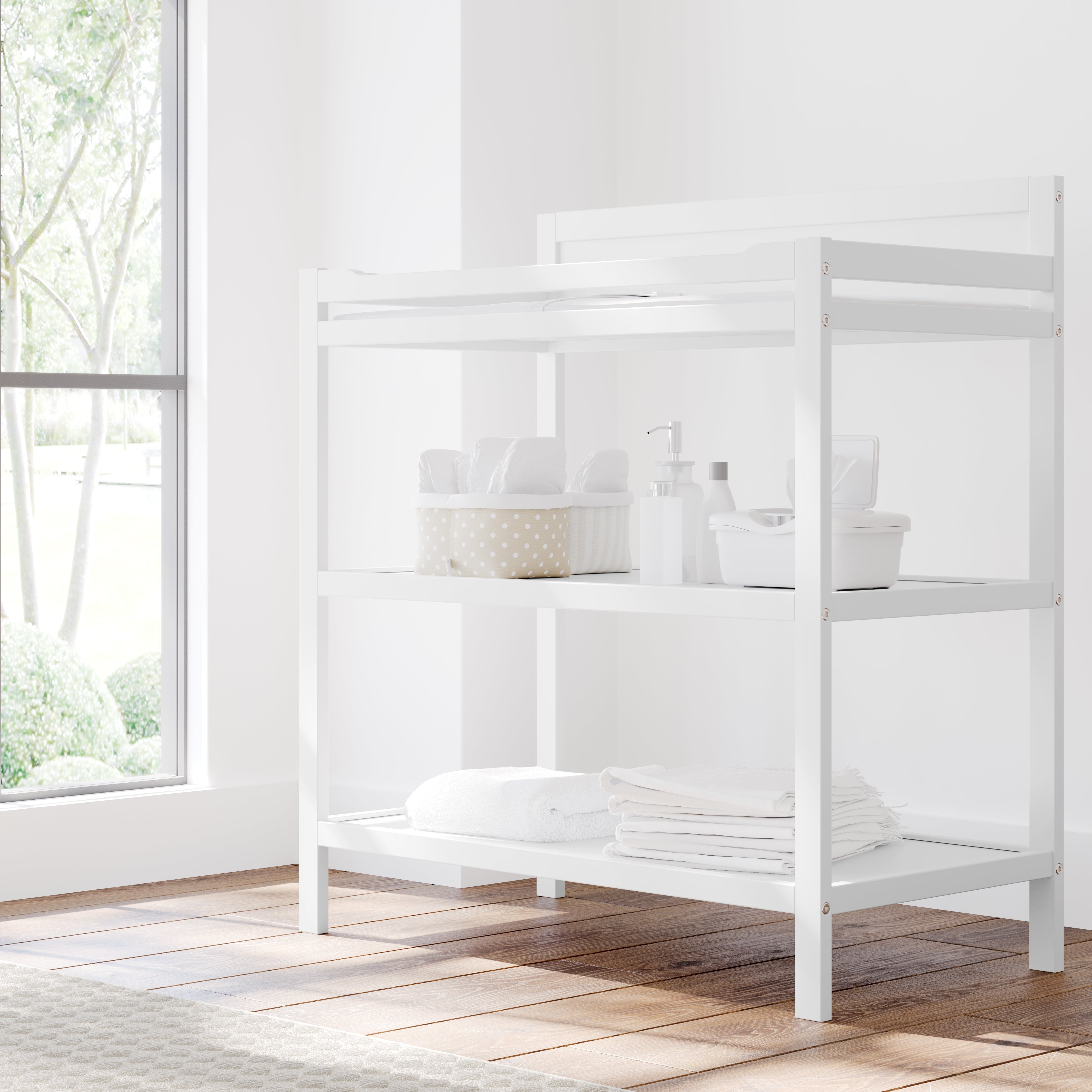 Angled view of white changing table with storage in nursery