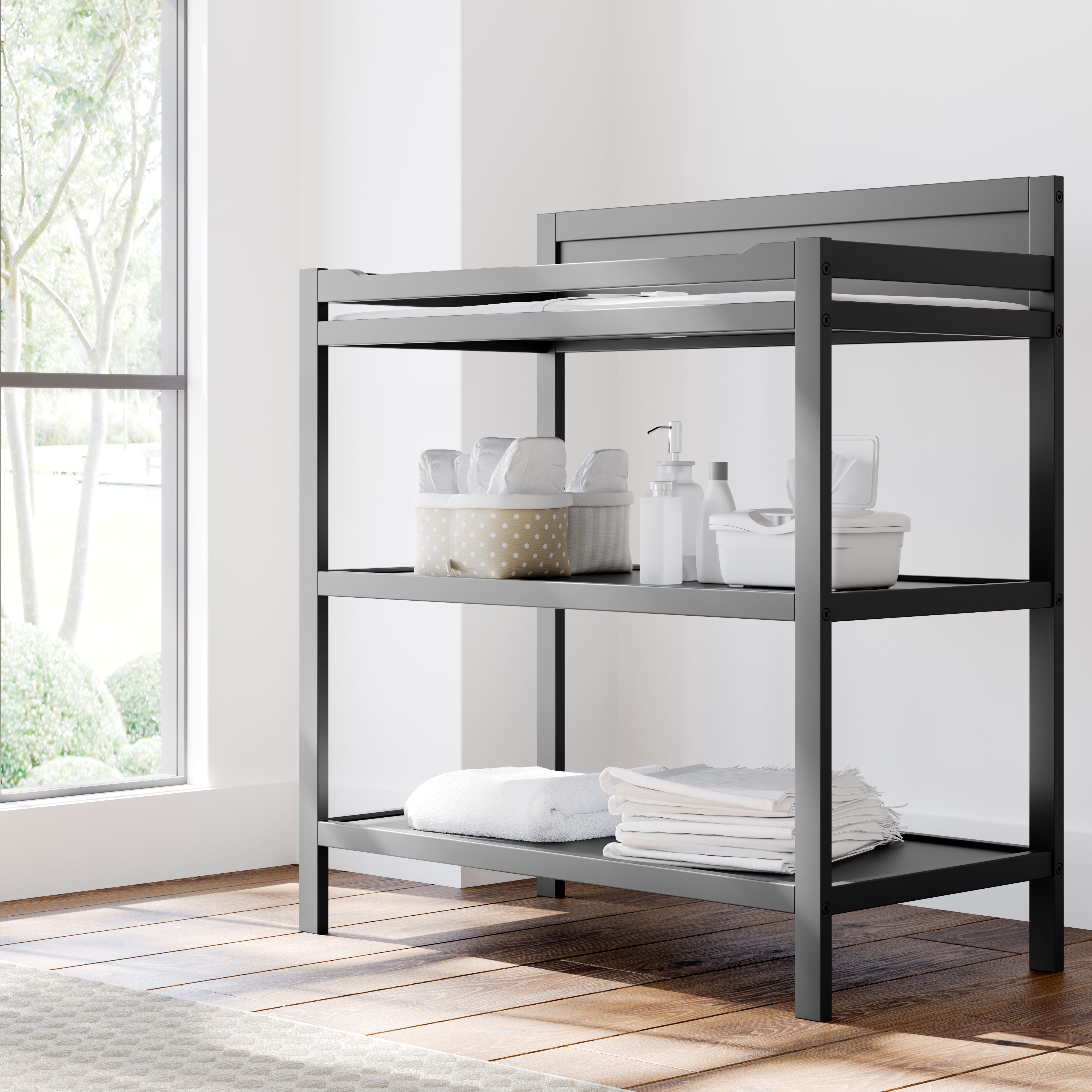 Angled view of gray changing table with storage in nursery
