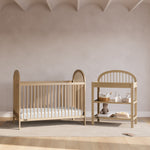 Olivia driftwood changing table in a nursery next to crib