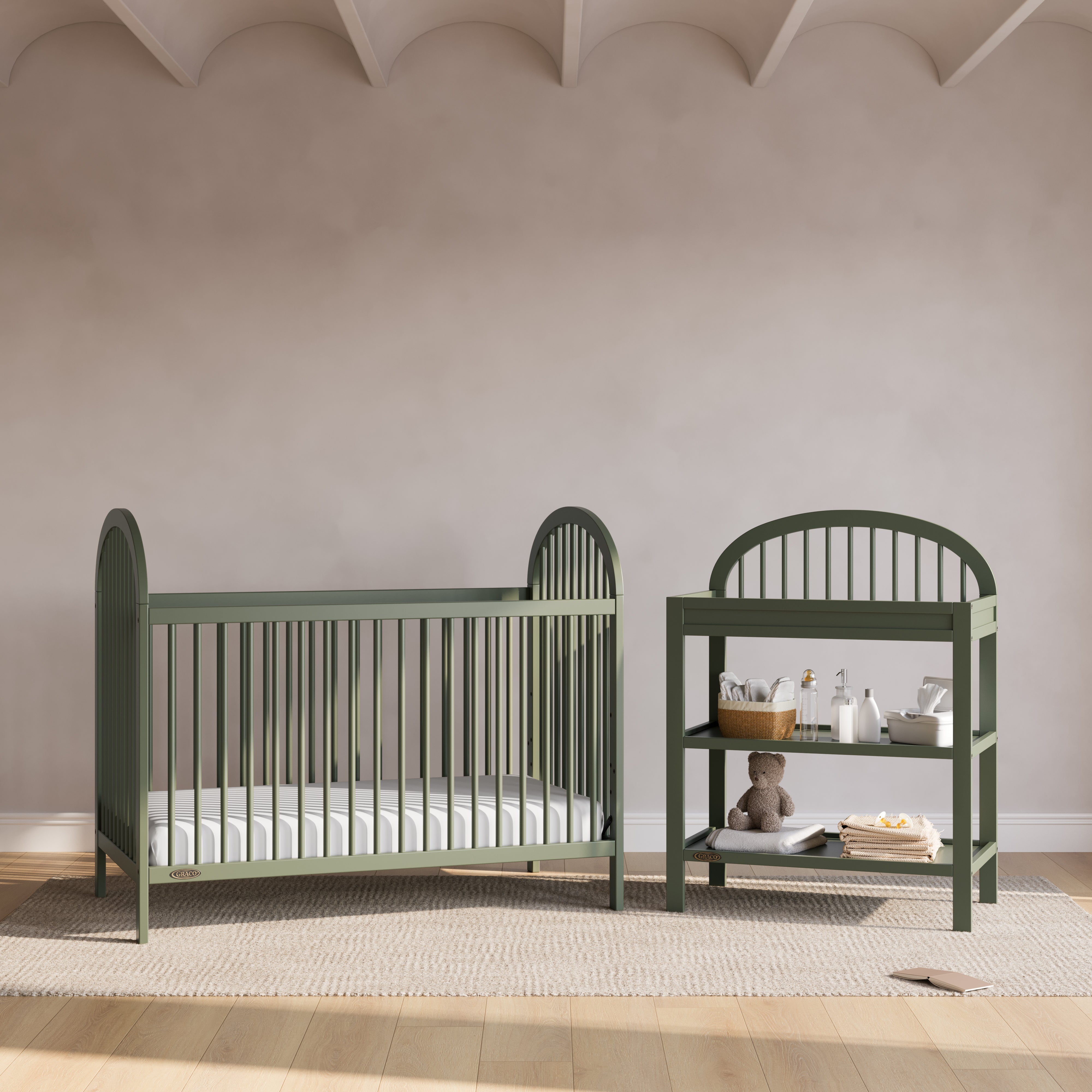 Olivia olive changing table in a nursery next to crib