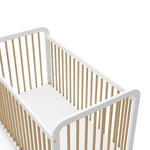 Close-up view of white with driftwood crib's headboard