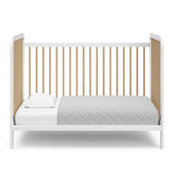White crib with driftwood in toddler bed conversion