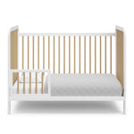 White crib with driftwood in toddler bed conversion with one safety guardrail