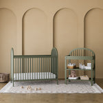 Olivia olive changing table in a nursery next to crib