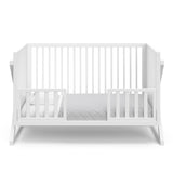 White crib in toddler bed conversion with two safety guardrails