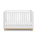 Front view of a white crib with a natural wood color base