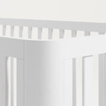 Close view of the rounded posts of a white crib.