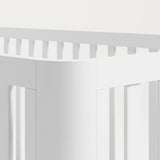Close view of the rounded posts of a white crib.