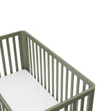 top view of a white crib with a natural wood color base